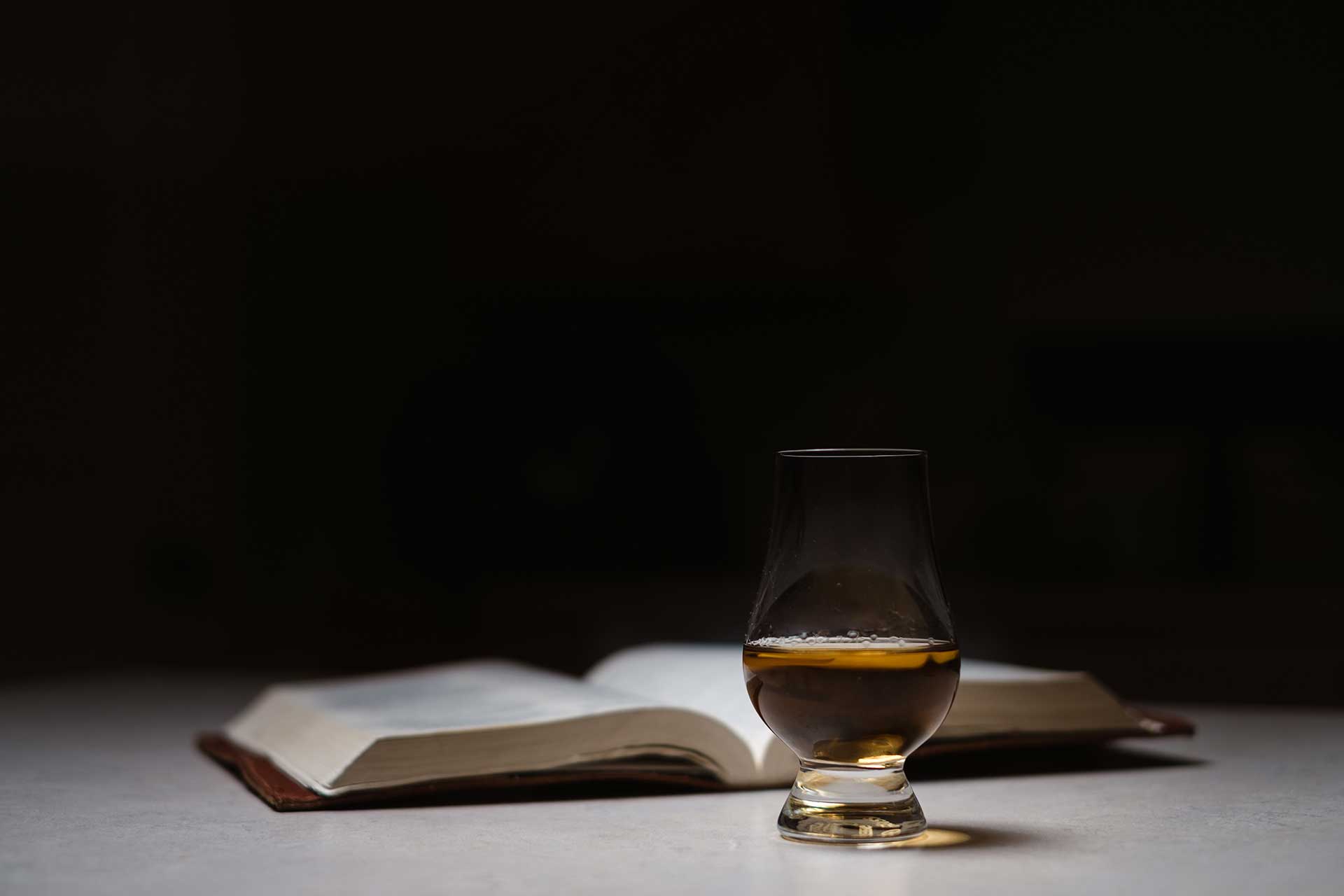 Glass of whisky and a book on a table.