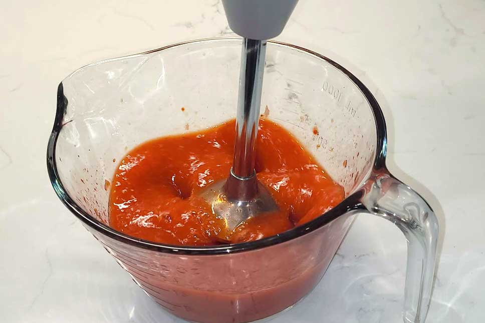 Blending strawberries with a hand blender.