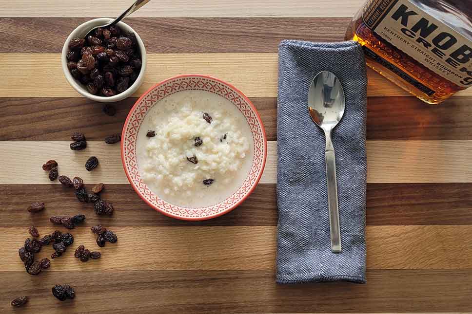 Rice pudding, raisins, and bourbon on a table.