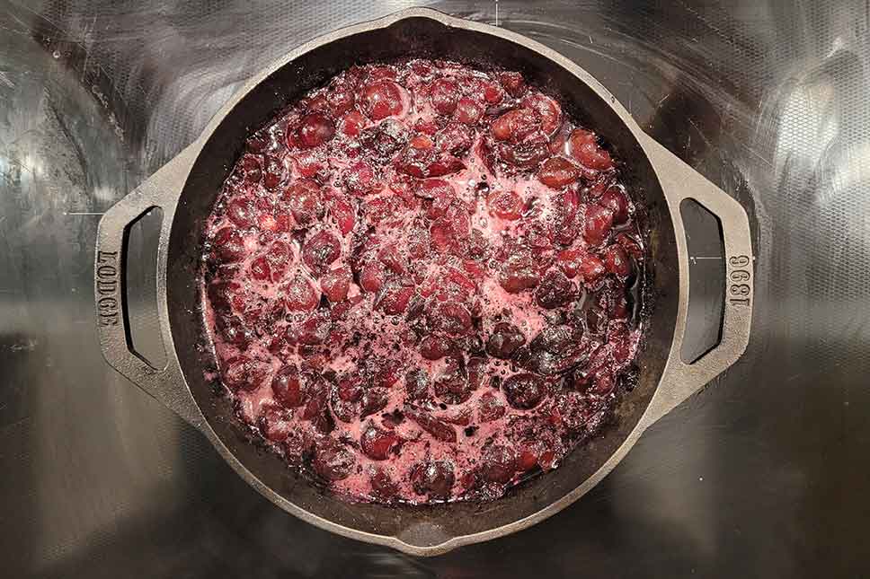 Smoked cherries in a cast iron pan on the stove.