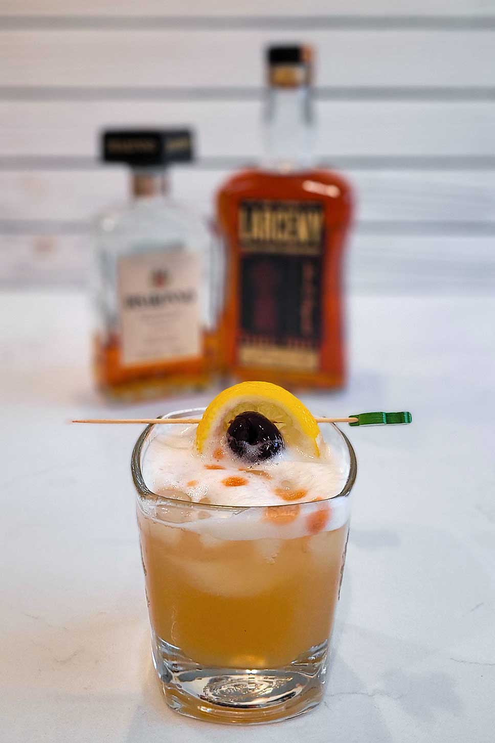 The amaretto sour with a lemon slice and cherry garnish.