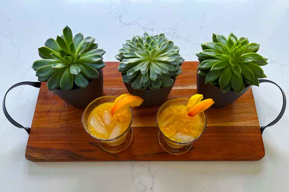 Two peach martinis on a cutting board.
