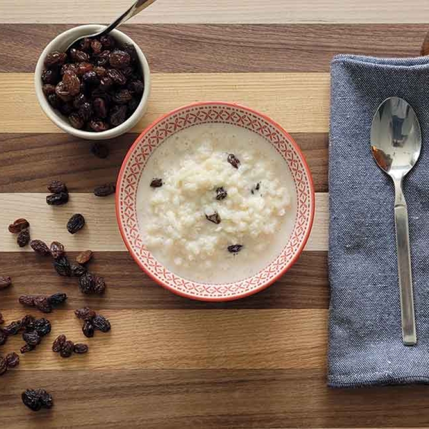 Rice pudding, raisins, and bourbon on a table.