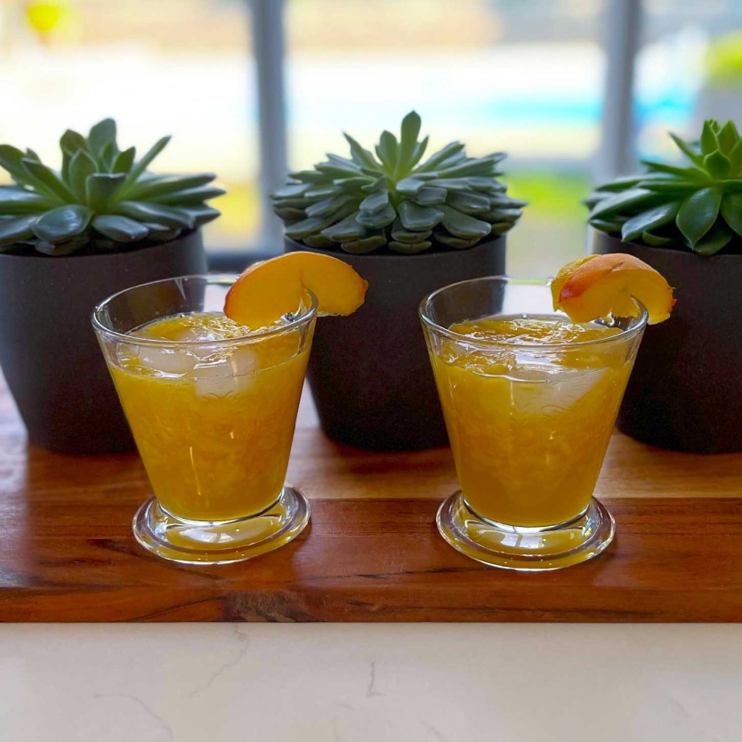 Two Rustic Peach Martinis on a cutting board.