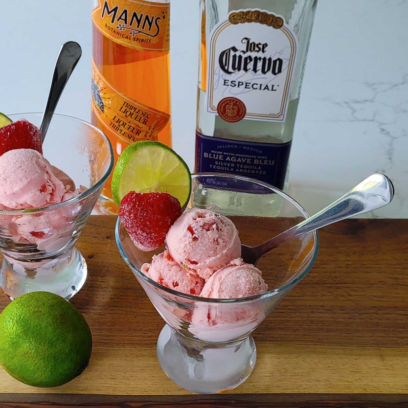 Two bowls of Strawberry Margarita Ice Cream with strawberries and lime.