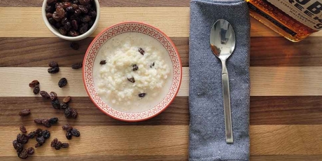 Rice pudding, raisins, and bourbon on a table.