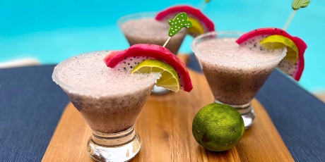 3 Dragon Fruit Margaritas on a tequila cutting board by a pool.