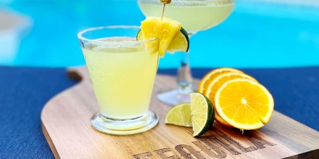 Pineapple Maragaritas on a cutting board by a pool.