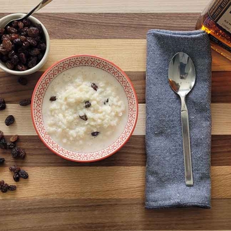 Rice pudding, raisins, and bourbon on a table.