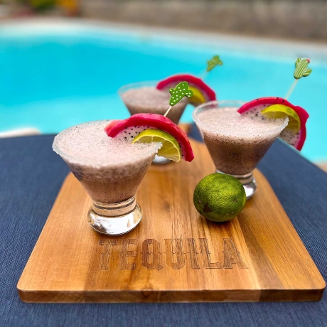 3 Dragon Fruit Margaritas on a tequila cutting board by a pool.