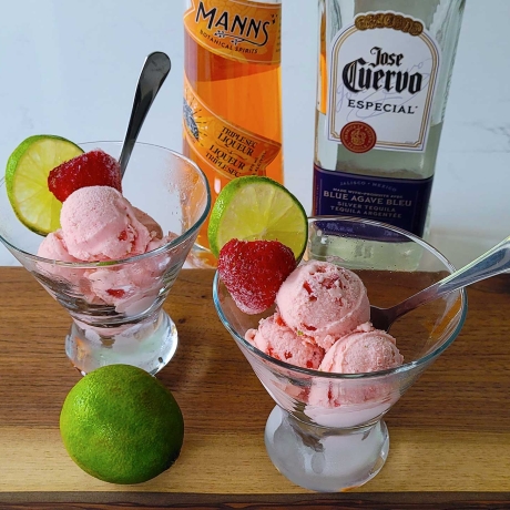 Two bowls of Strawberry Margarita Ice Cream with strawberries and lime.