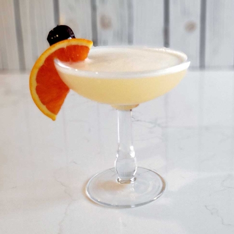 The classic whiskey sour with an orange slice and cherry garnish.