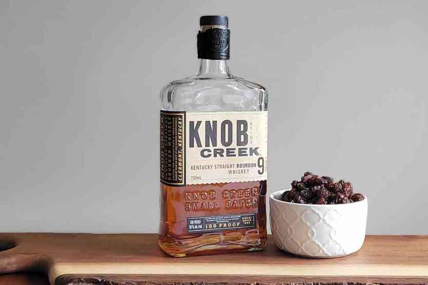 Raisins and a bottle of bourbon on a table.