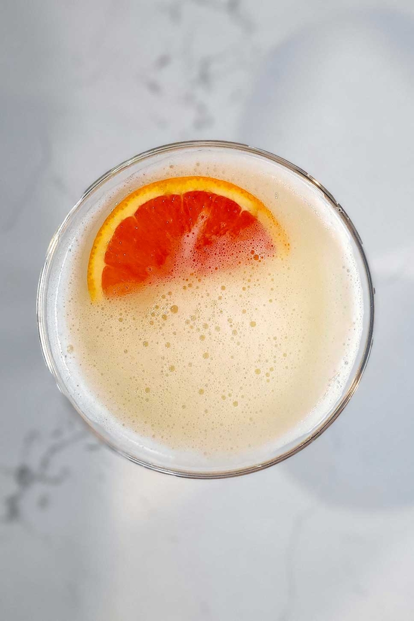 A whisky sour with an slice of orange for a garnish.