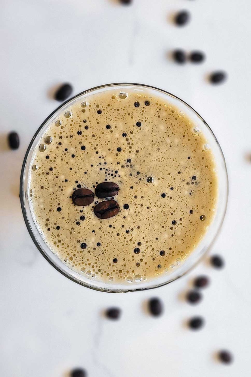 Espresso martini on a counter with whole coffee beans.