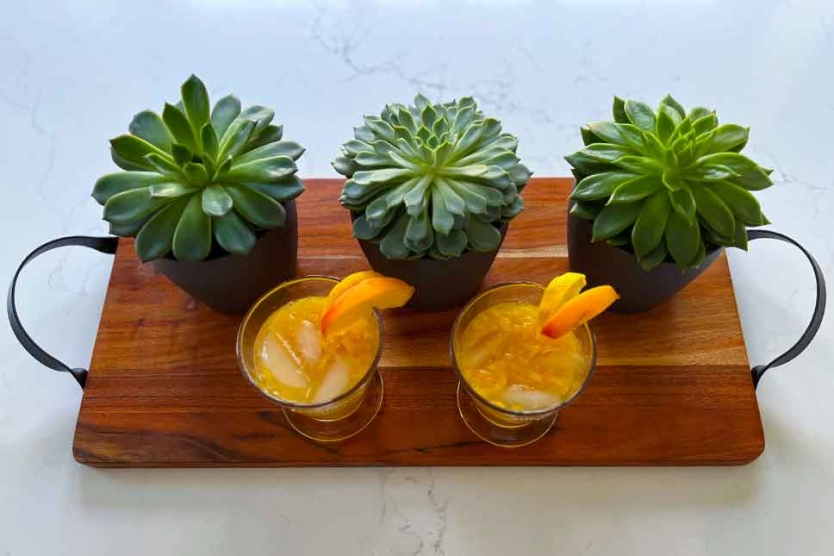 Two peach martinis on a cutting board.